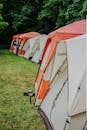 Long line of tents in scenic forest campsite during daytime, perfect for outdoor adventures.