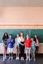 A diverse group of smiling students posing with their teacher in a cheerful classroom setting, marking the first day back to school.